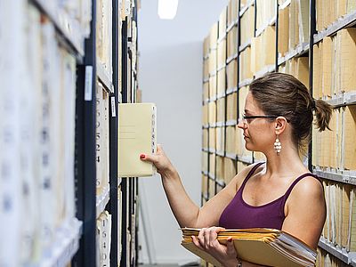 uni-assist Mitarbeiterin sortiert Akten ins Archiv ein.